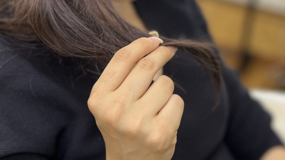 鏡の前で毛先を気にする手元